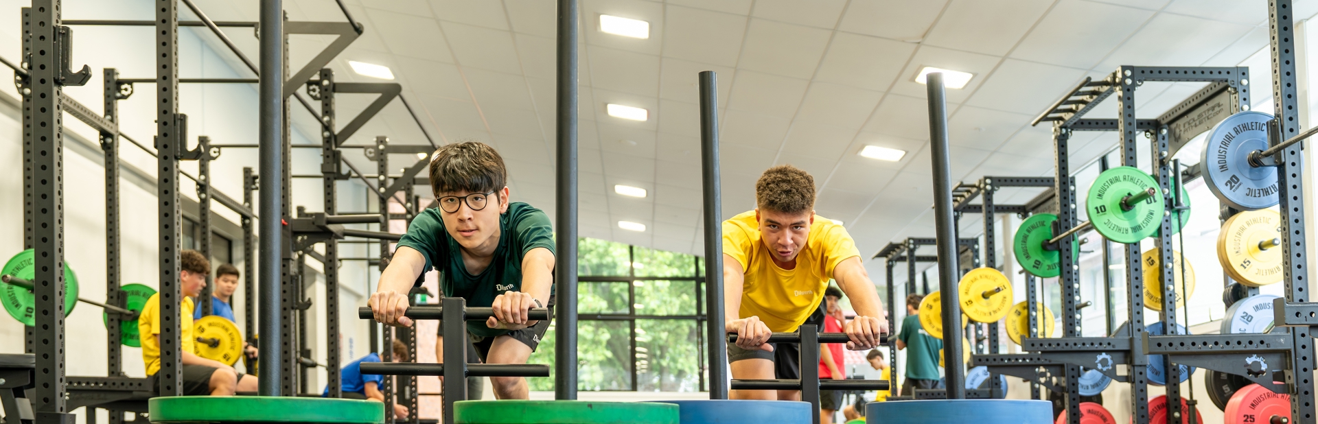 two boys pushing weights across the gym floor 