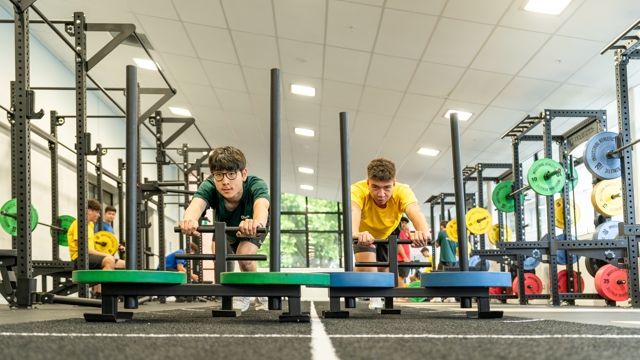 two boys pushing weights across the gym floor