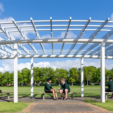 boys sitting under a pergola reading and talking 