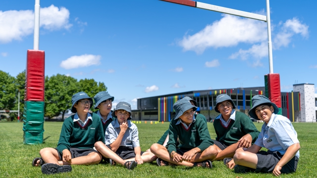 boys sitting on a rugby field under goal posts
